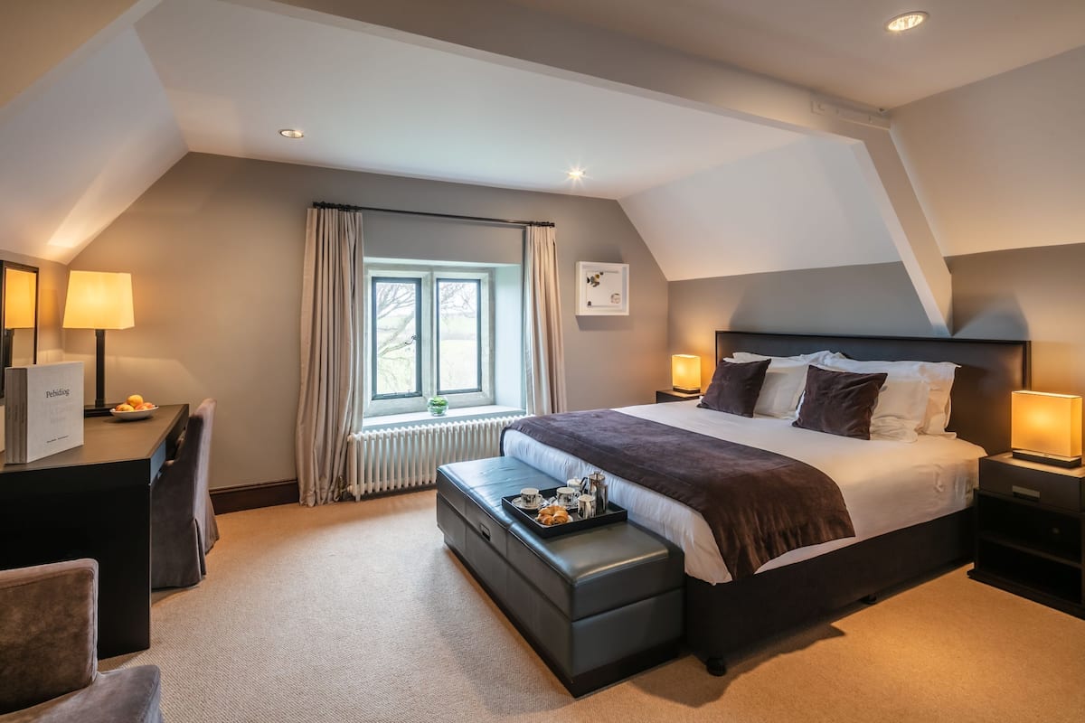 A modern hotel room with a large bed, a desk, and a window with curtains.