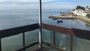 A view from a balcony overlooking a calm body of water with boats, a pier, and buildings in the distance. - Hoedjiesbaai Hotel (Saldanha)