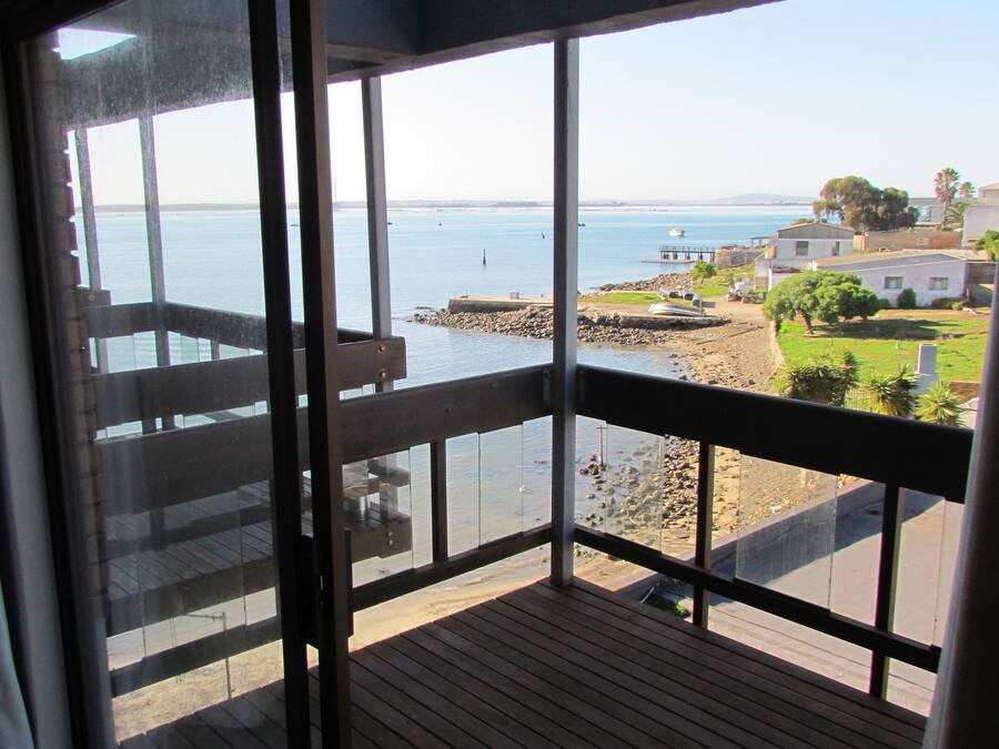 A balcony with a view of the sea and a small pier.