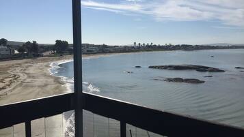 Blick aufs Meer und den Strand von einem Balkon mit Geländer.