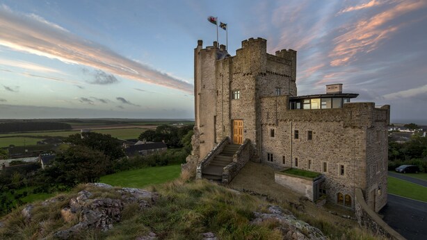 A historic stone castle with a prominent tower, a modern annex, and a flag on top. - Roch Castle Hotel (Haverfordwest)