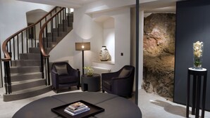 A modern living room with a staircase, dark leather sofas, a coffee table with books, a lamp, and a decorative vase. - Roch Castle Hotel (Haverfordwest)