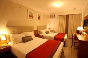 A hotel room with two beds, a desk, a chair, and a television. - Royal Macaé Palace Hotel (Macaé)
