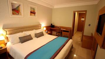 Una habitación de hotel con una cama grande, un escritorio, una silla y un televisor.