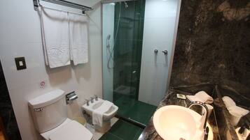 Casa de banho com sanita, bidé, cabine de duche com vidro e lavatório.