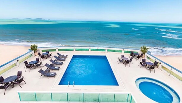 A pool area with lounge chairs and a view of the ocean. - Royal Macaé Palace Hotel (Macaé)