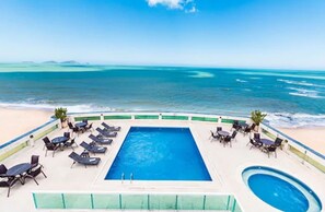 Zona de piscina amb gandules i vista a l'oceà.