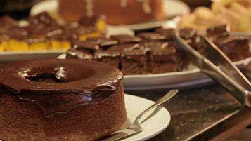 A chocolate cake with a glossy finish on a white plate, accompanied by a fork.