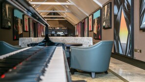 Ein Klavier in einem geräumigen Zimmer mit hohen Decken, einer Bar und Sitzgelegenheiten.