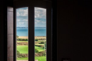 Vista a través de una puerta que muestra campos y una masa de agua distante.