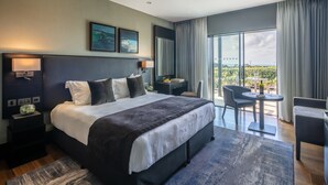 Ein modernes Hotelzimmer mit einem großen Bett, einem Schreibtisch und einem Balkon mit Tisch und Stühlen.
