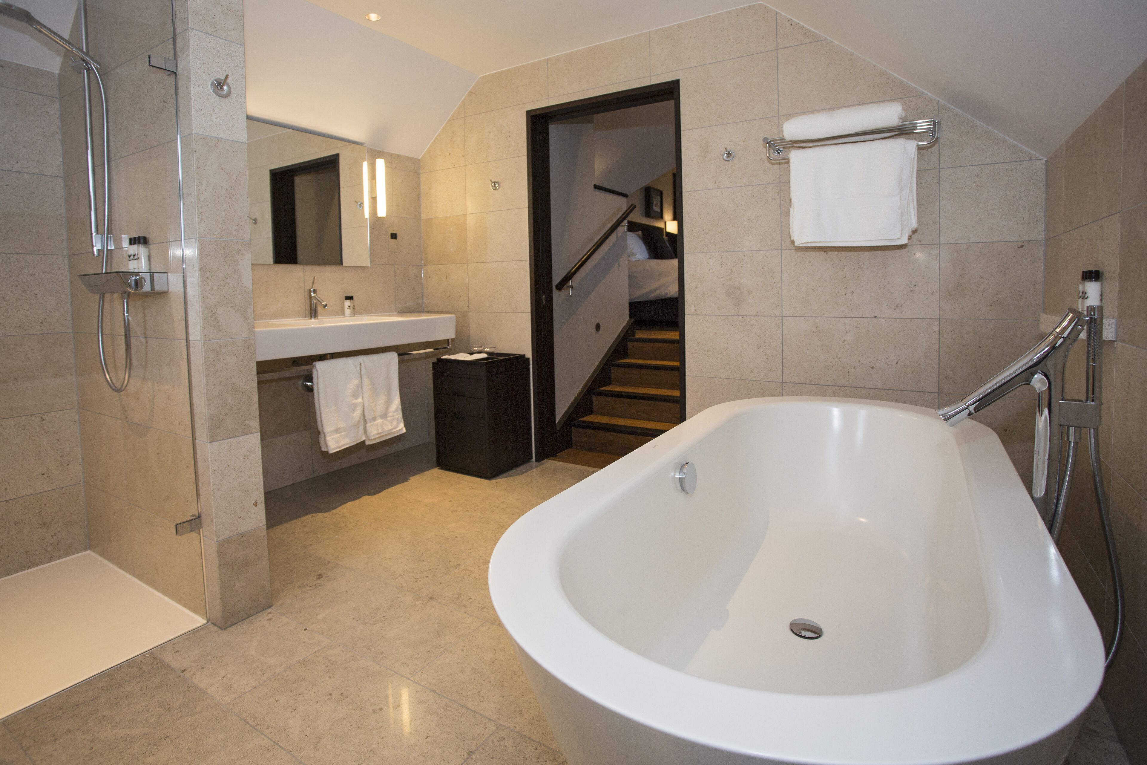 Un bagno moderno con una grande vasca da bagno, una zona doccia, un lavandino e uno specchio.