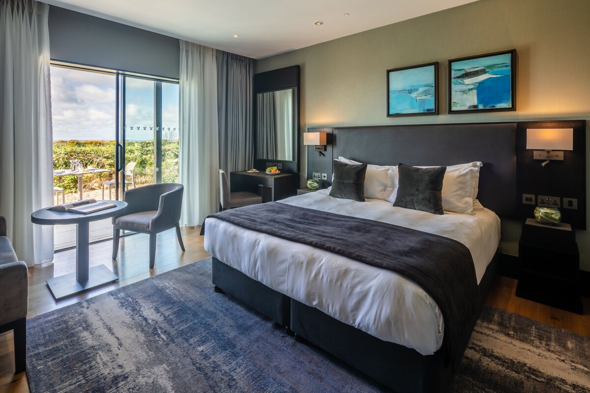 Une chambre d’hôtel moderne dotée d’un grand lit, d’un bureau, d’une chaise et d’un balcon avec vue.