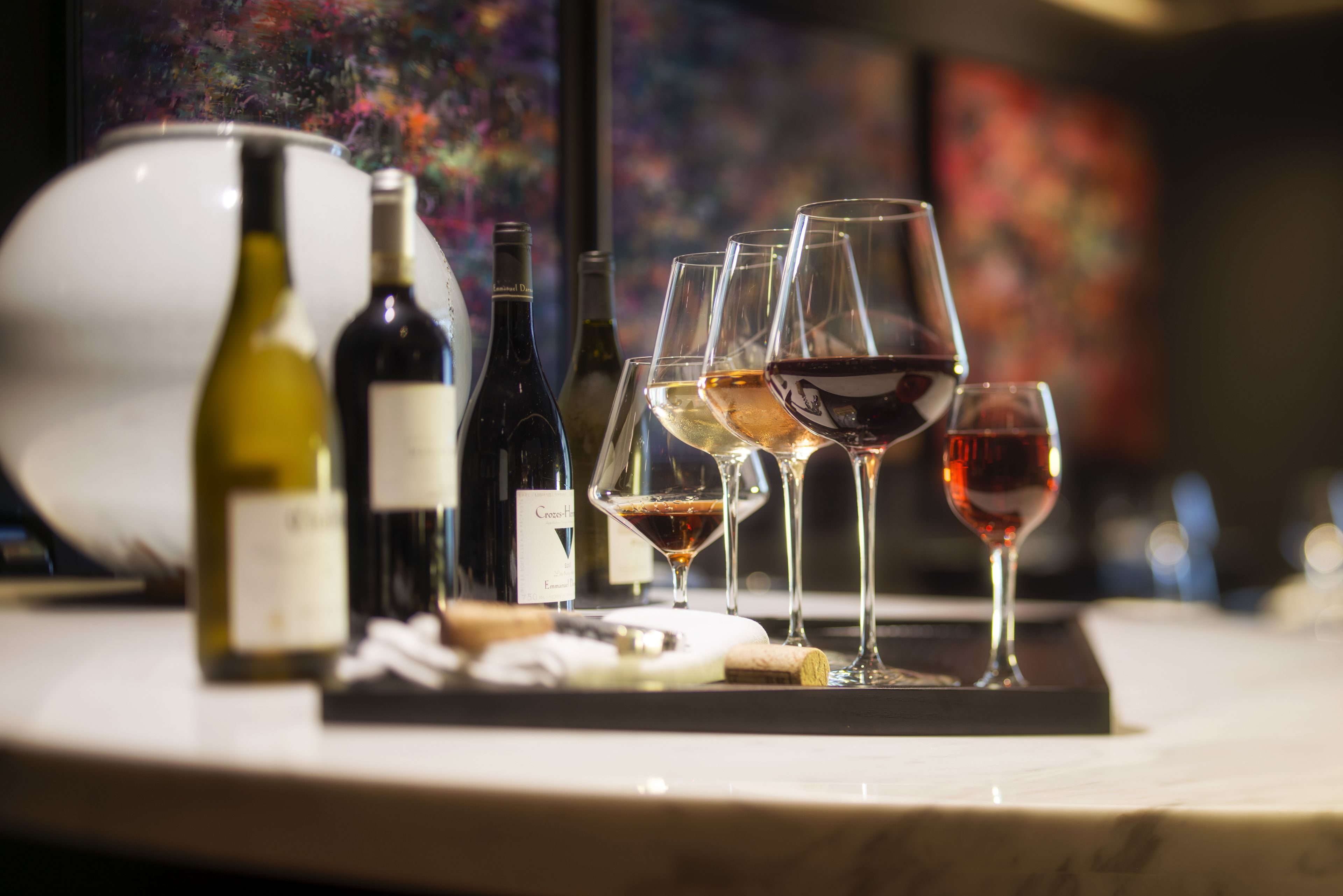 Una degustación de vinos con varias botellas y copas sobre una encimera de mármol.
