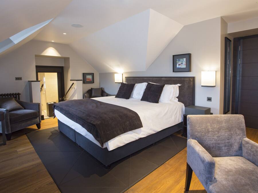 A modern bedroom with a large bed, a chair, and a desk.