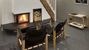 Un intérieur moderne avec une cheminée, un escalier en bois et un coin salon comprenant une table et des chaises.