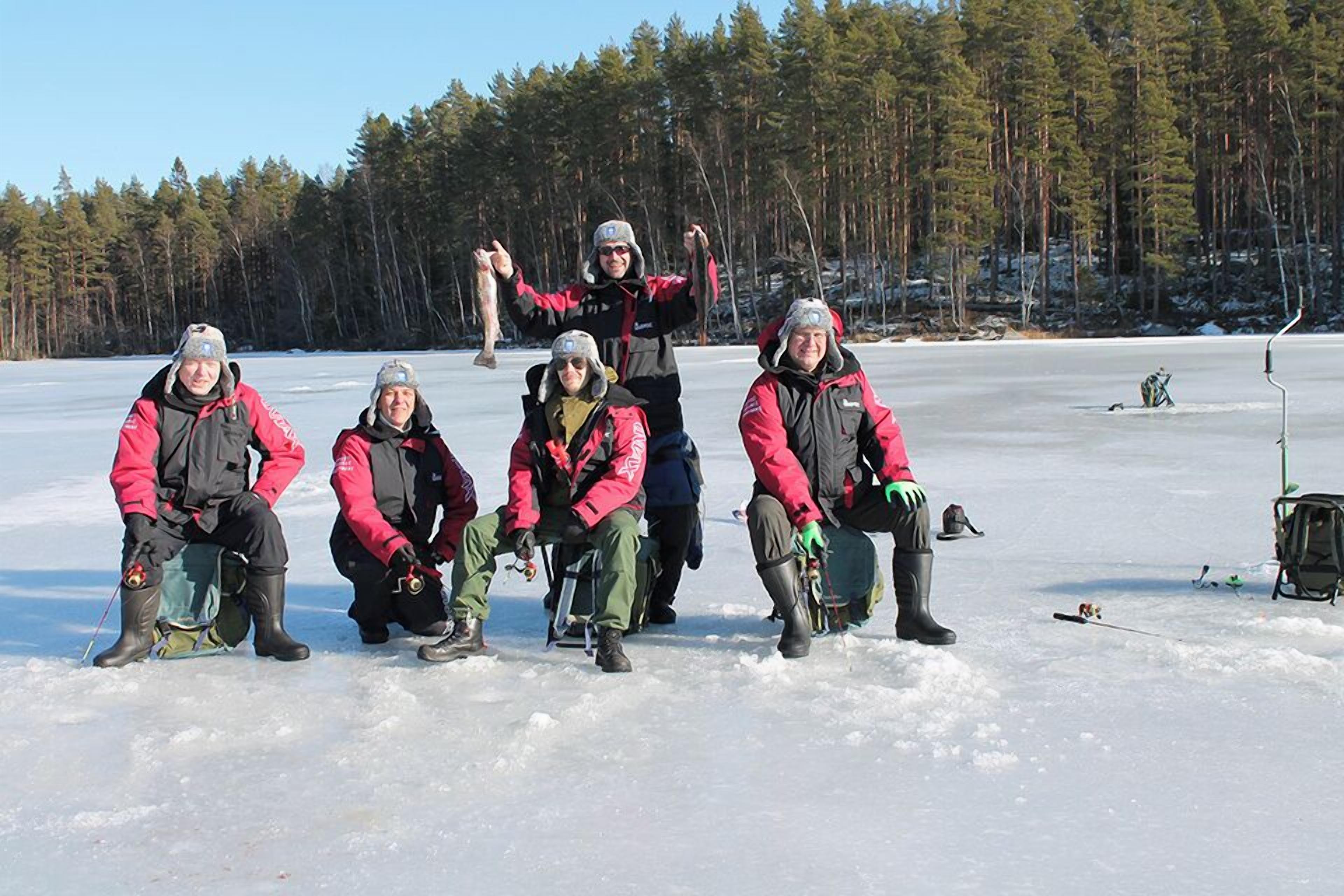 A group of people in winter gear on a snowy landscape with trees in the background.