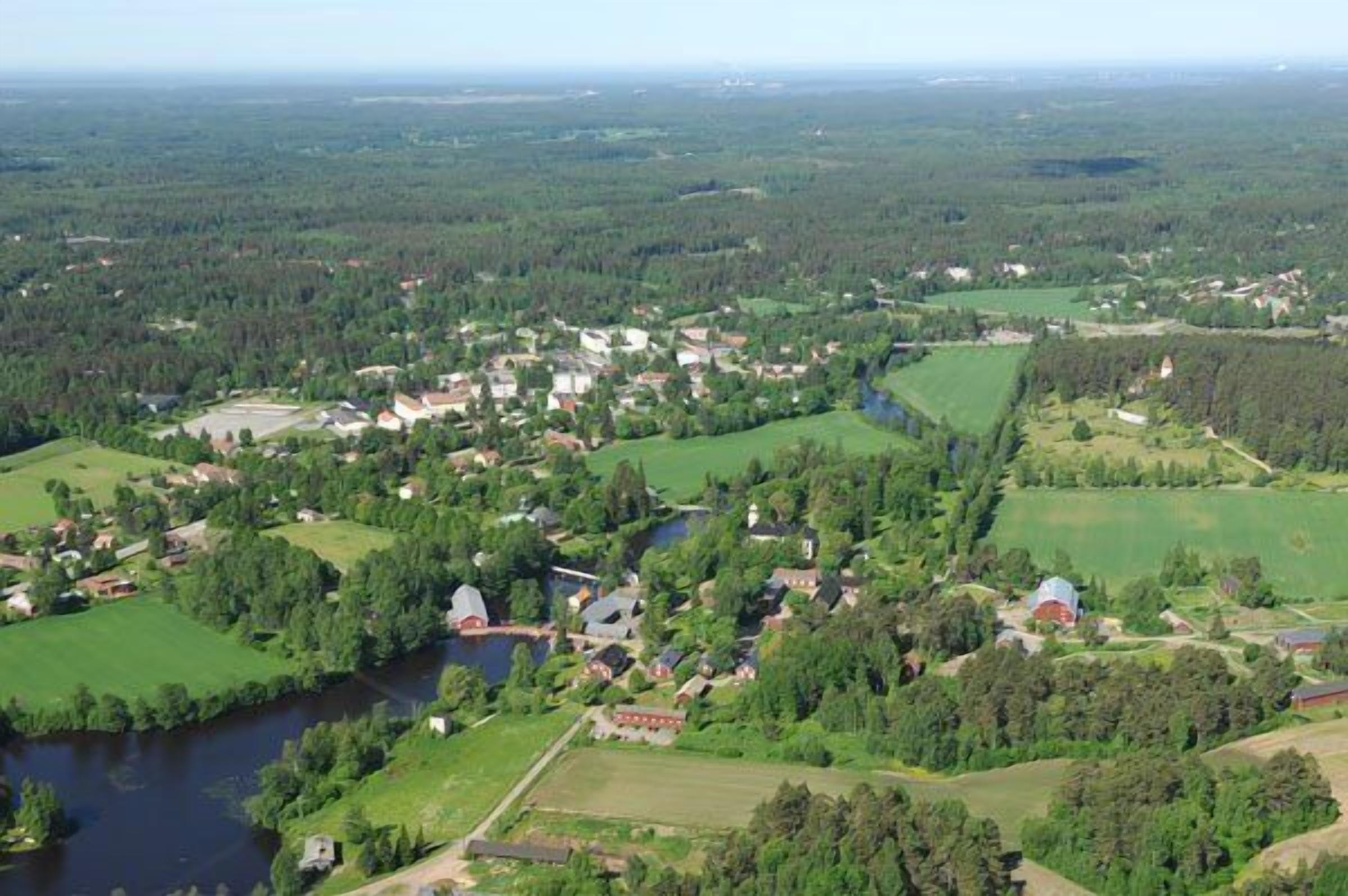 An aerial view of a rural area with scattered houses, fields, and a river.