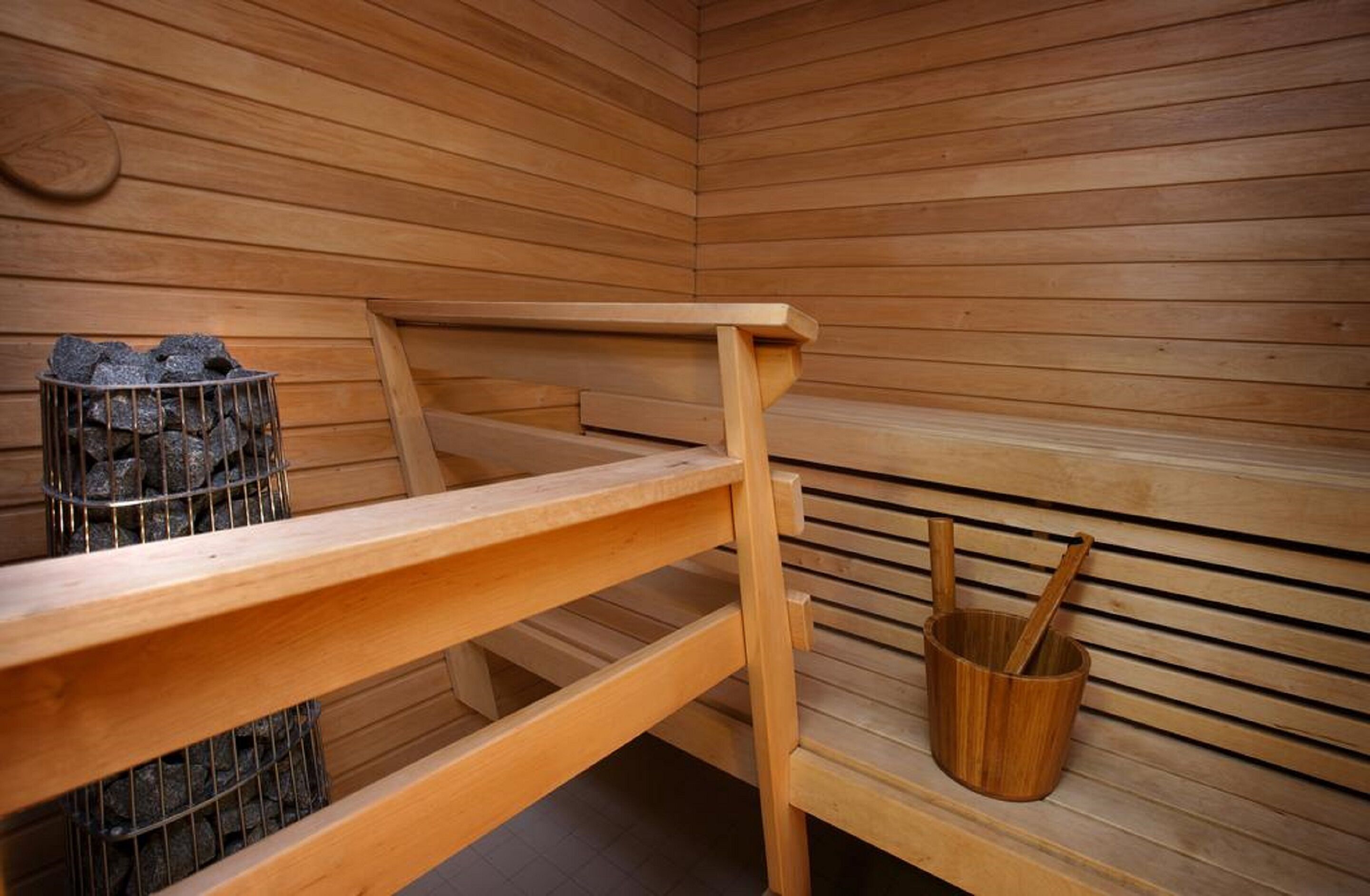 A wooden sauna with benches and a wooden bucket.