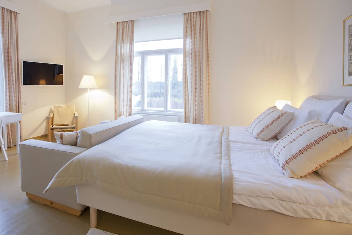 Een slaapkamer met een groot bed, een bureau, een stoel en een televisie.