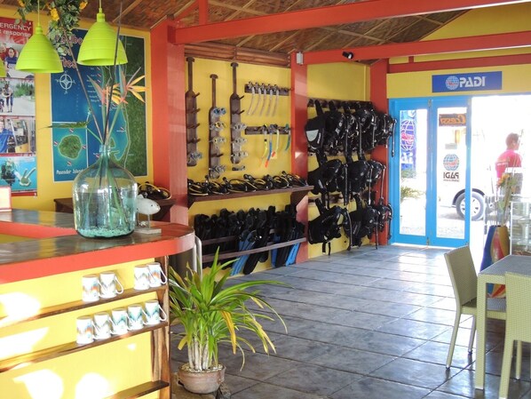 Una tienda colorida con estantes llenos de mochilas negras y una exhibición de tazas blancas.