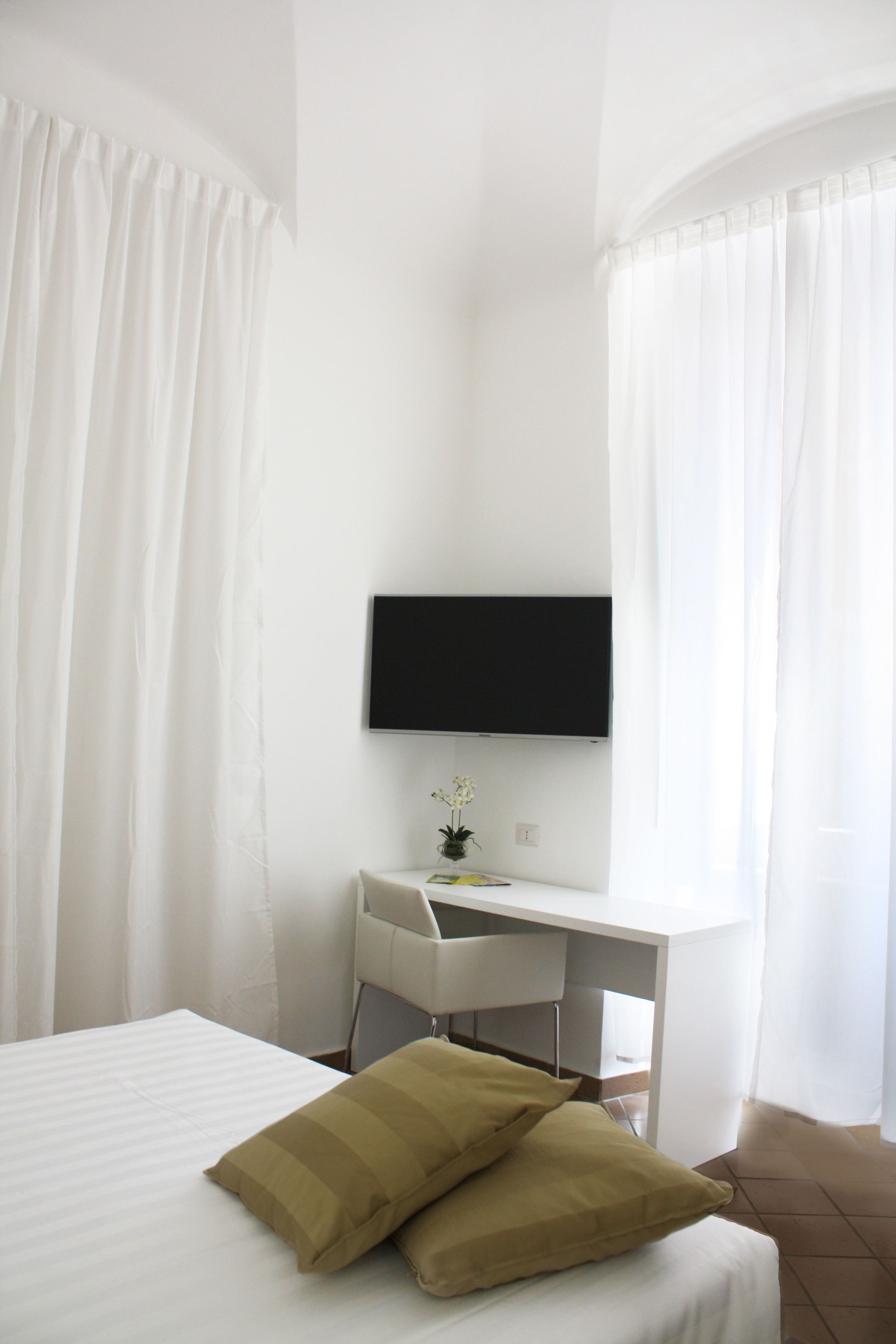 A bedroom with a bed, a desk, and a TV.