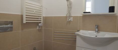 A bathroom with a bidet, a sink, a mirror, and a towel rack.