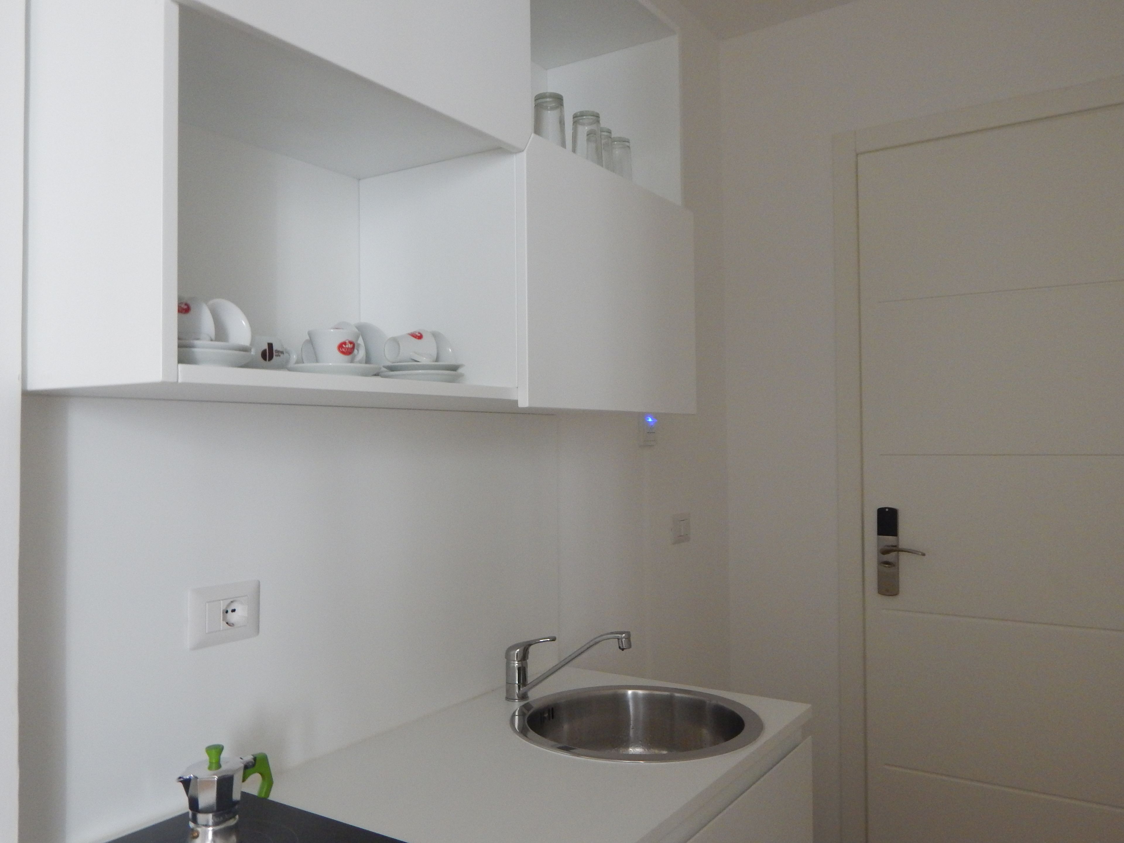 Un baño moderno con un lavamanos blanco, un espejo encima y una puerta a la derecha.