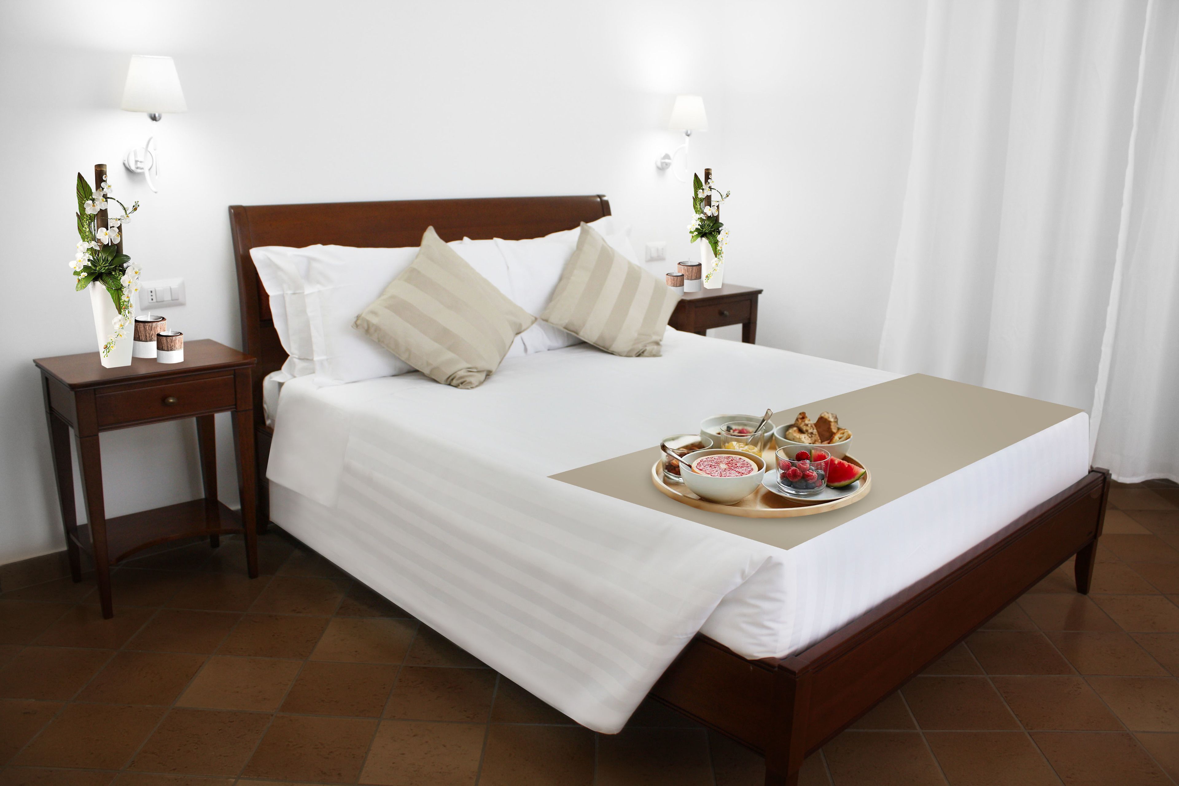 Una cama bien hecha con una bandeja de desayuno, dos mesitas de noche con lámparas y un cabecero de madera.