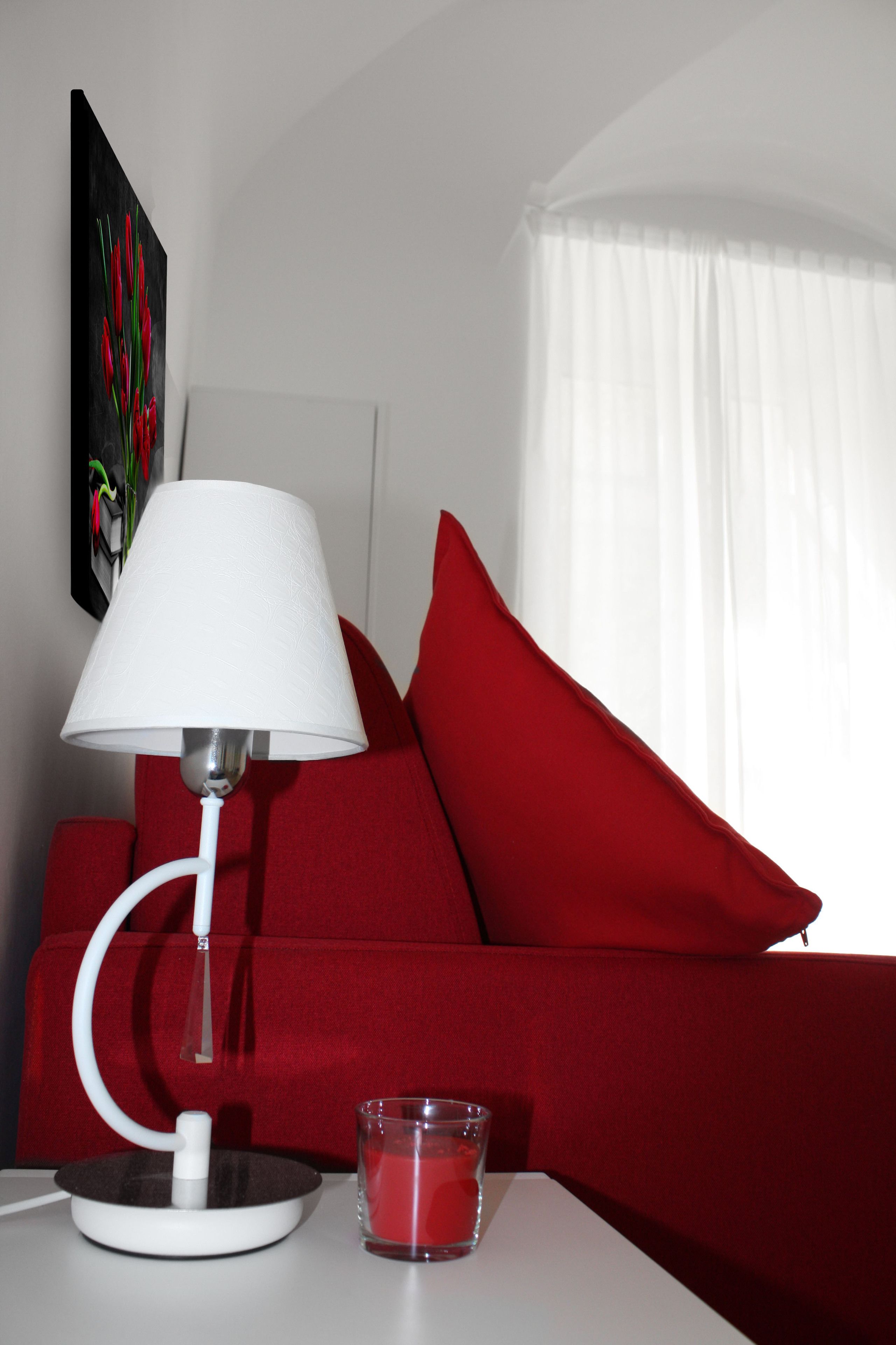 Ein modernes Zimmer mit einem weißen Tisch, einem roten Sofa, einer weißen Lampe und einem Glaslüster.