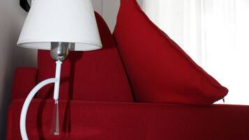 Ein modernes Zimmer mit einem weißen Tisch, einem roten Sofa, einer weißen Lampe und einem Glaslüster.