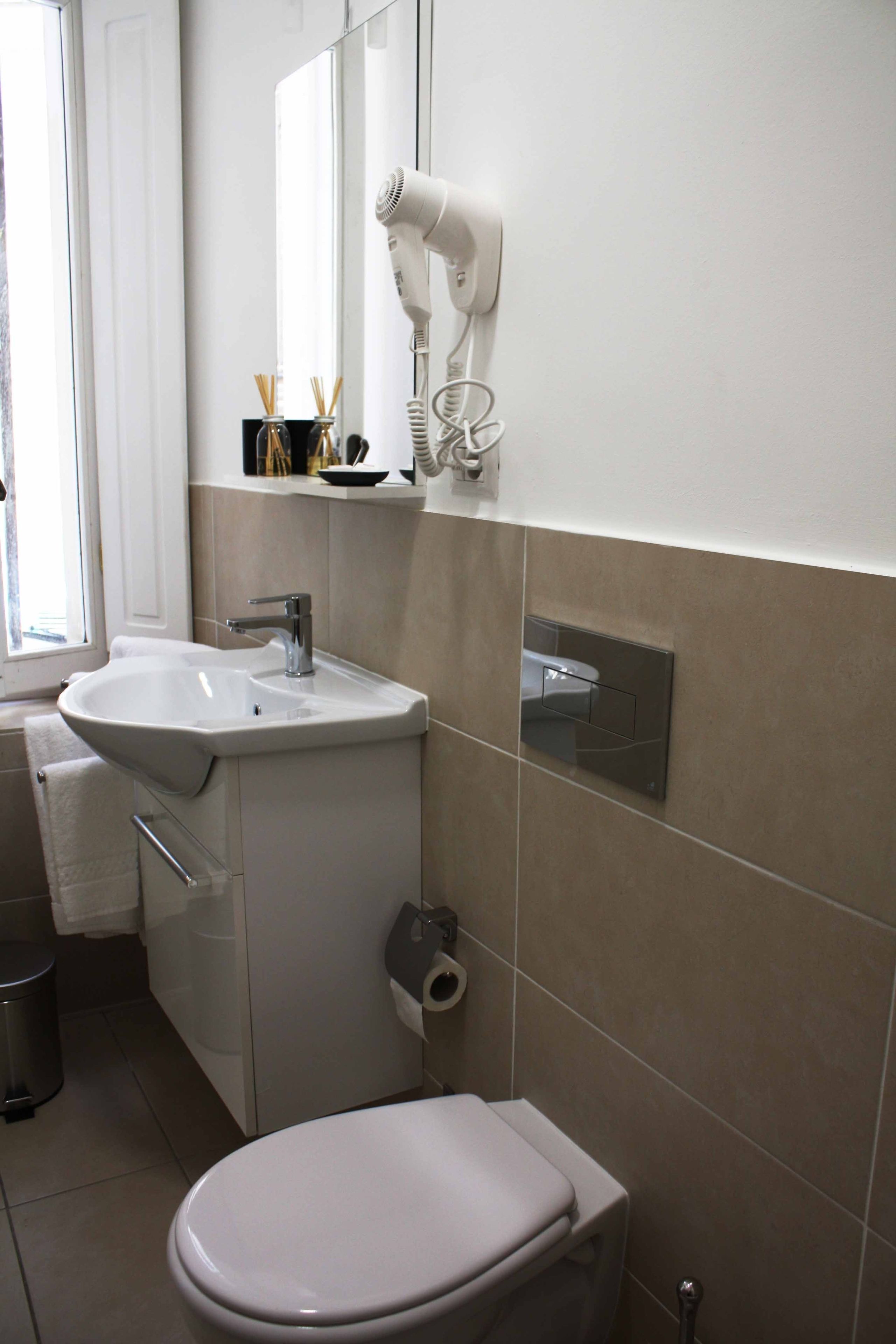 A bathroom with a white sink, a mirror, a hairdryer, and a toilet.