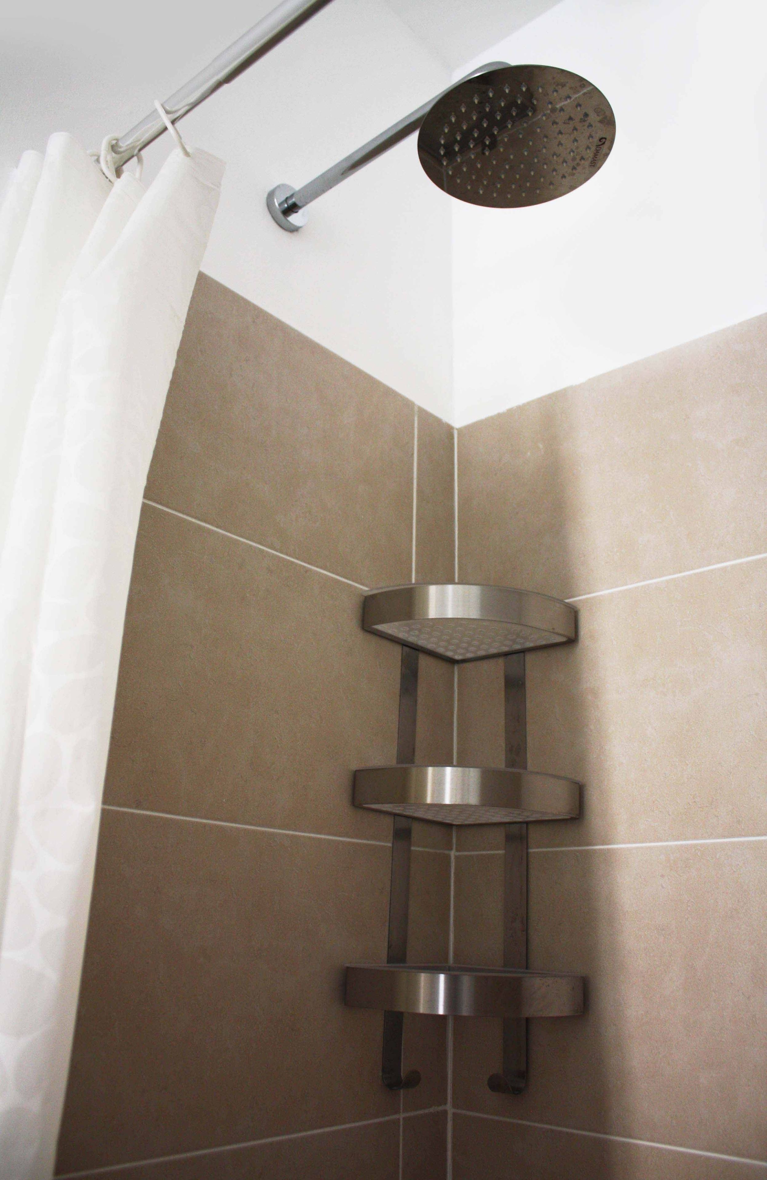 A shower with a handheld showerhead and a wall-mounted control panel.