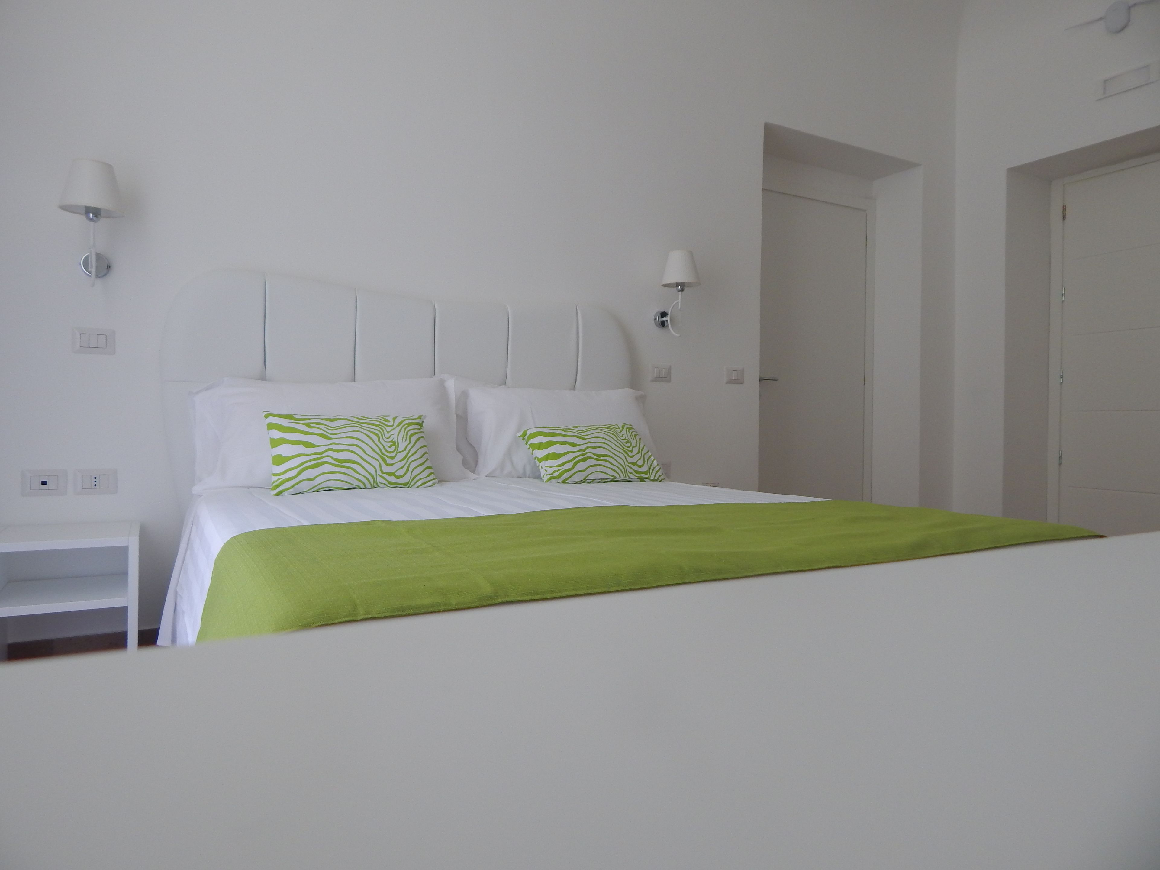 A neatly arranged bedroom with a bed, two bedside tables, and a door.