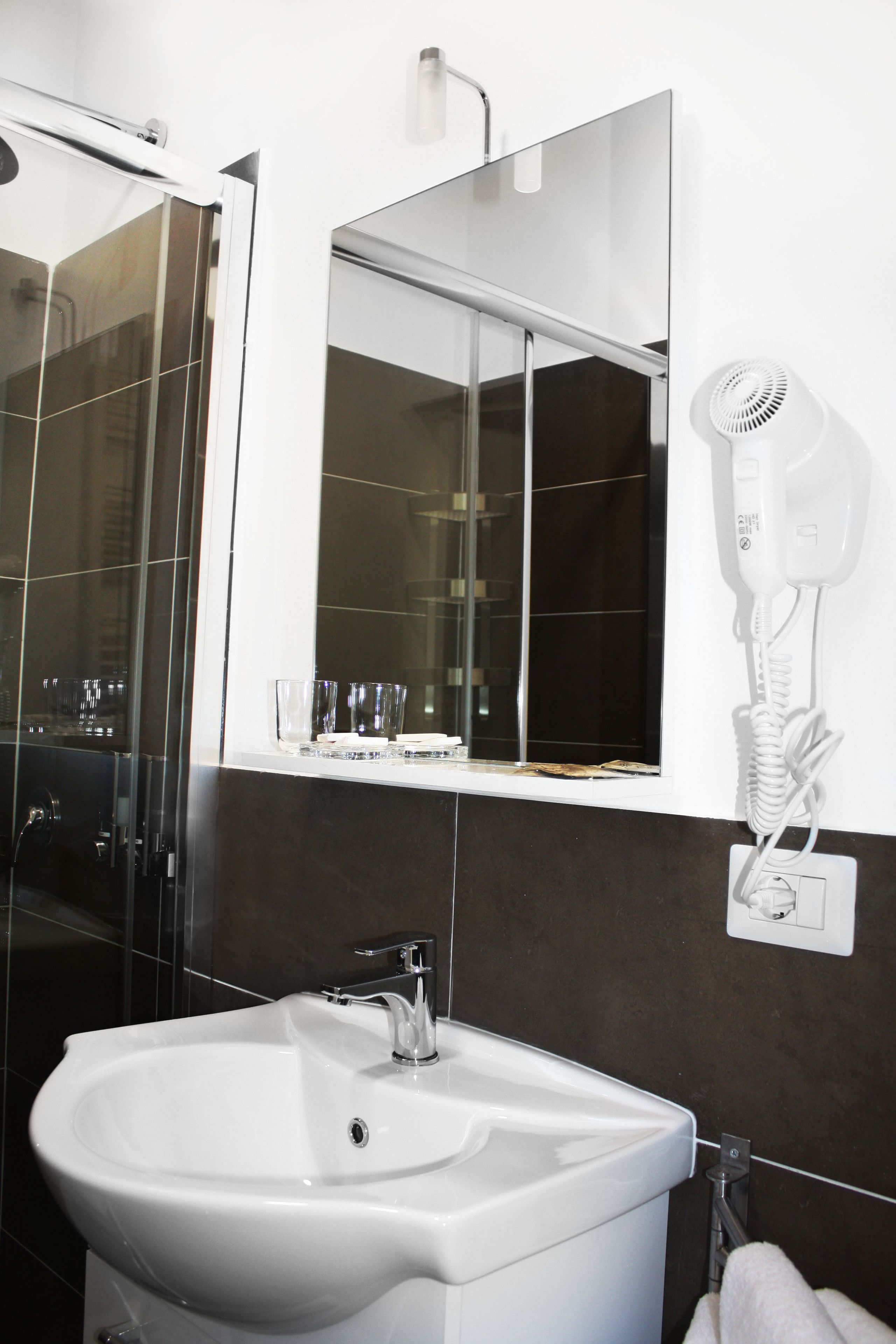 A bathroom with a white sink, a mirror, and a hairdryer mounted on the wall.