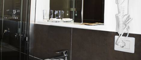 A bathroom with a white sink, a mirror, and a hairdryer mounted on the wall.