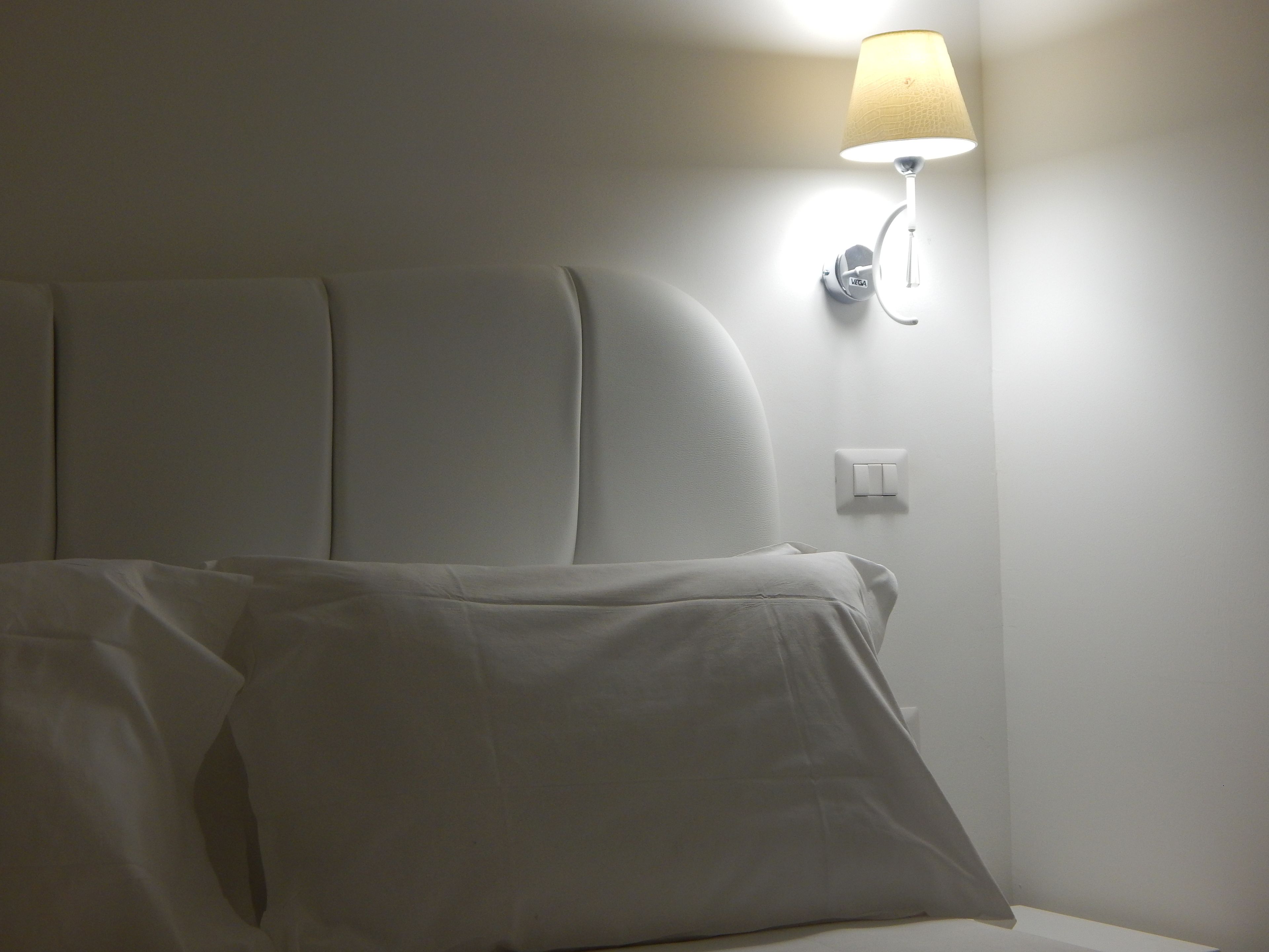 Cama bem arrumada com lençóis brancos em quarto de hotel.