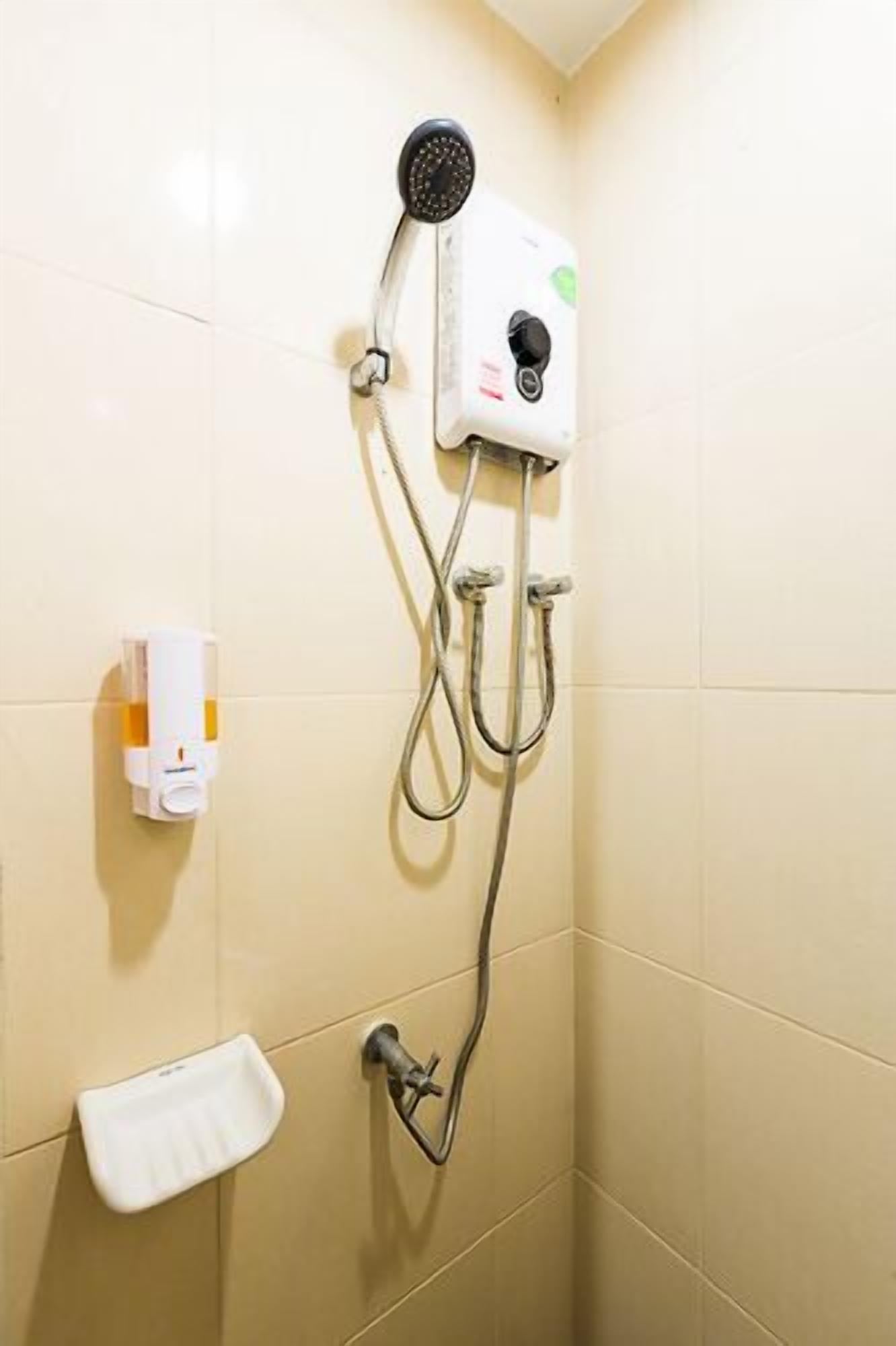 A shower with a handheld showerhead, a handheld soap dispenser, and a handheld towel dispenser.