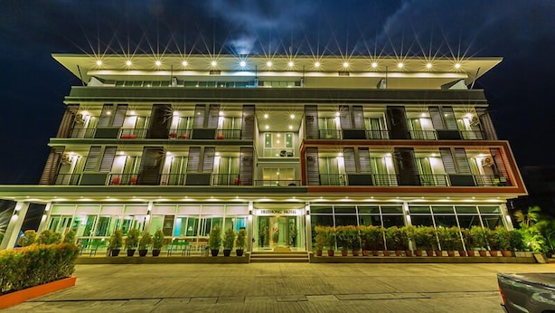 Un hôtel à plusieurs étages au design moderne, doté de balcons et d’une entrée bien éclairée.