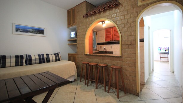 A compact living space with a sofa, a small kitchen area with stools, and a television. - Copacabana 705 B (Rio de Janeiro)