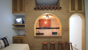 A compact room with a bed, a small TV, a kitchen area with a microwave, and three stools. - Copacabana 705 B (Rio de Janeiro)