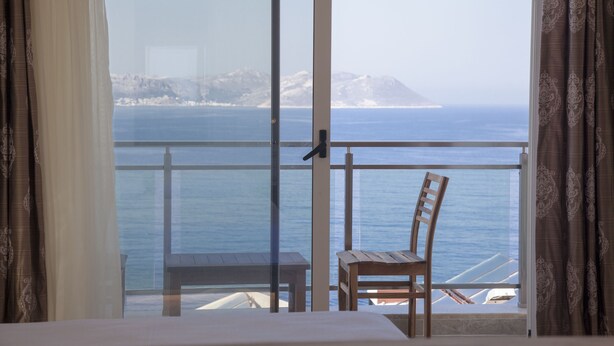 A room with a view of the sea, a wooden chair, and a table. - Narr Twin (Kas)