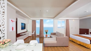 A modern hotel room with a dining area, a sofa, a bed, and a TV.