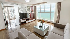 A modern living room with a flat-screen TV, a glass coffee table, and a sofa.