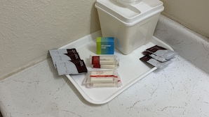 A bathroom with a toilet, a shower cap, and toiletries on a tray.