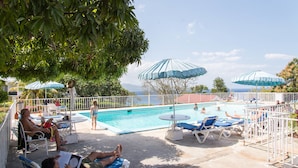 A pool area with lounge chairs and umbrellas, surrounded by a white fence. - Skymiles Beach Suite At  Montego Bay Club Resort (Montego Bay)