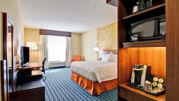 A hotel room with a bed, desk, chair, television, and a coffee maker.