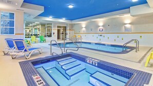 An indoor swimming pool with clear water, blue tiled steps, and lounge chairs. - Fairfield Inn and Suites by Marriott Kamloops (Kamloops)