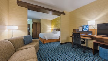 A hotel room with a bed, a desk, a chair, a sofa, and a television.