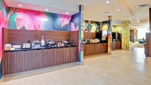 A modern reception area with a wooden reception desk, a large floral mural, and a seating area with a view. - Fairfield Inn and Suites by Marriott Kamloops (Kamloops)